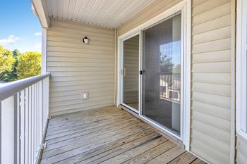 A deck with a sliding glass door leading to a balcony.